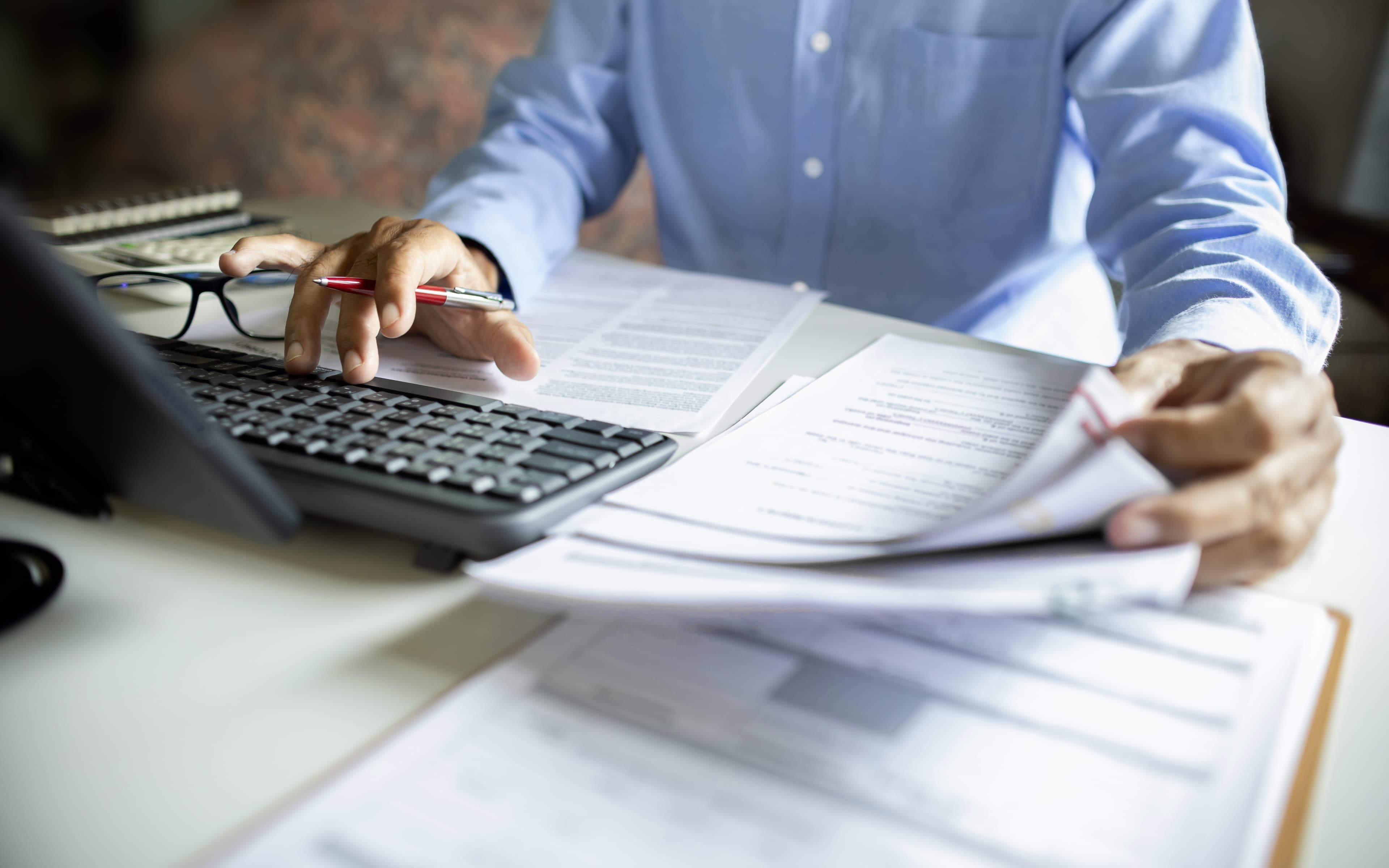 Person reviewing documents beside a calculator